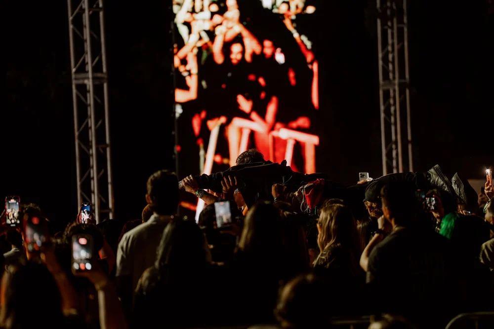 Night crowd with phones up in front of the big screen